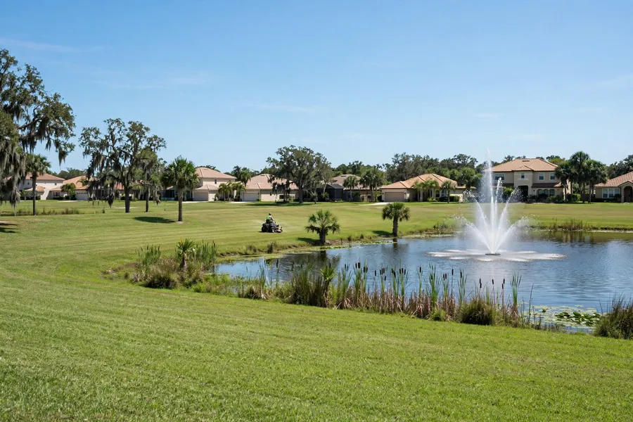 Crew mowing a common area lawn beside a retention pond in a Florida HOA